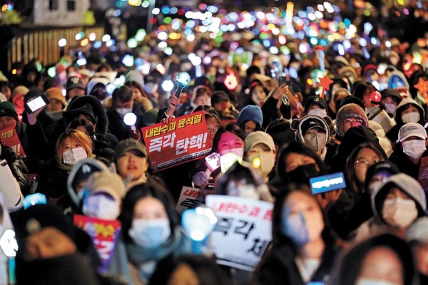 图为8日下午,在首尔汝矣岛国会前举行的呼吁弹劾和逮捕尹锡悦的烛光文化节上,参加者举着相关的牌子和应援棒。【照片来源:韩联社】