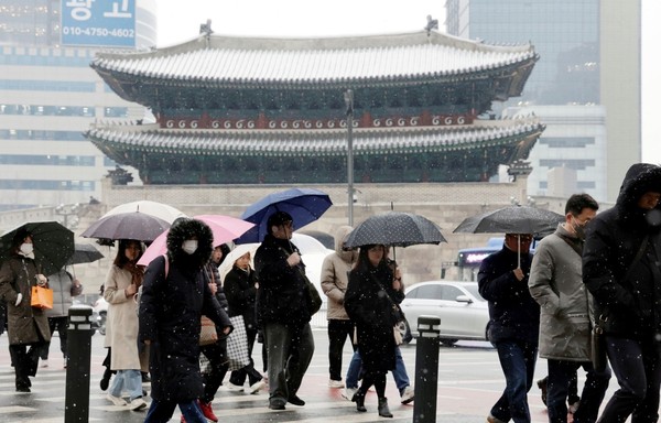 图为市民们走过下雪的首尔崇礼门附近。【照片来源：NEWS1】